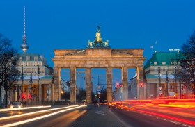 Brandenburger Tor mit Leuchtspuren und dem Fernsehturm Alex und Hotel Adlon